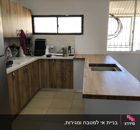 מטבח עם ארונות עץ, מכשירי חשמל ומשטח עבודה